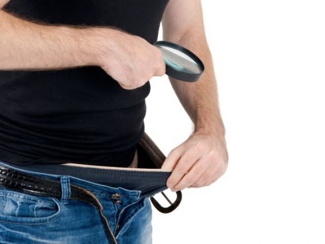 mężczyzna spogląda w dół swoich spodni i chce powiększyć swojego penisa